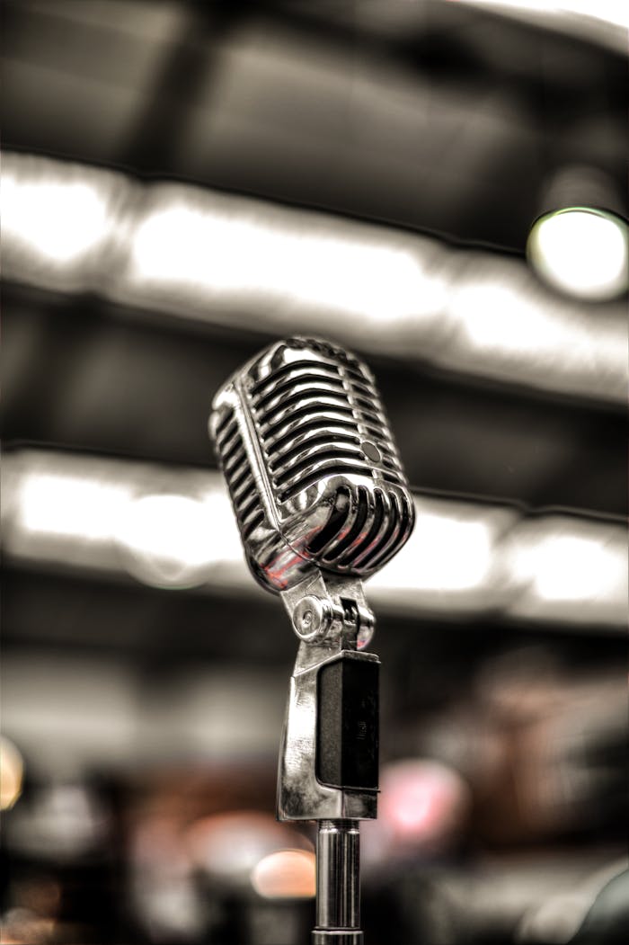 Close-up of a vintage chrome microphone on a blurred stage background, ideal for music themes.